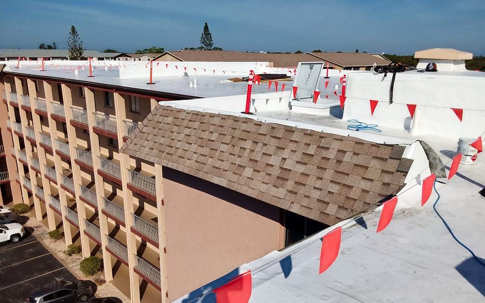 Multi-story residential building with flat roof sections and a shingled mansard during a Providential re-roof